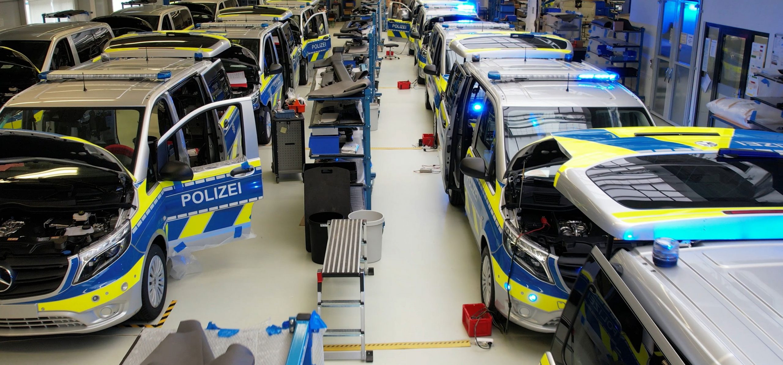 Hero Image Police Vans in Garage with Doors and Bonnets Open Parked in 2 Lines